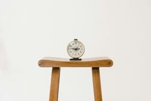A clock sitting atop a wooden stool